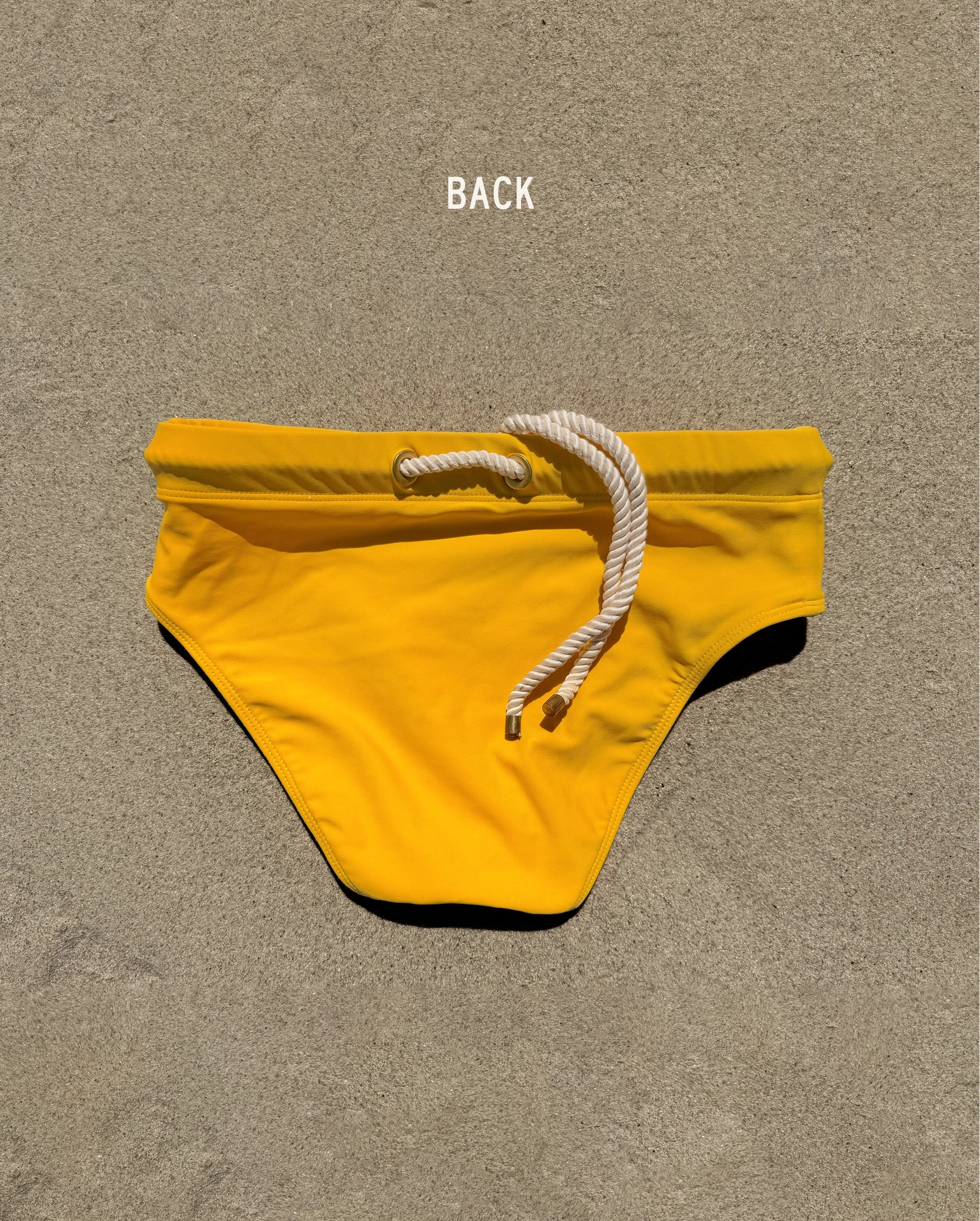 Detail back view of yellow Lobby’s Nippers swim briefs, highlighting the signature rope and brass eyelet waistband.