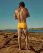 Model wearing yellow Lobby’s one-piece swimwear, back view highlighting open back and flattering fit.